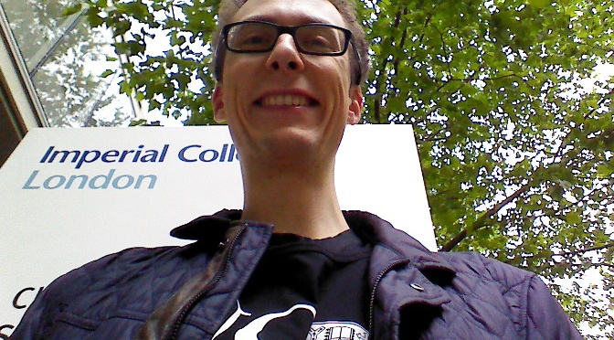 Timm in front of a sign at Imperial College London